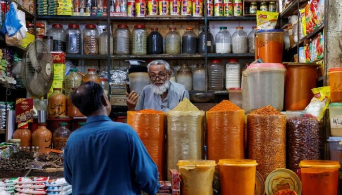 A shopkeeper speaks with a customer while selling spices at a market in Karachi. — Reuters/File