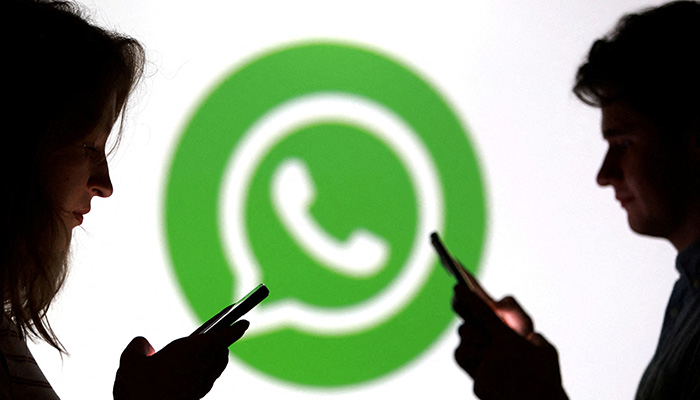 Teenagers pose for a photo while holding smartphones in front of a Whatsapp logo in this illustration taken September 11, 2025. — Reuters